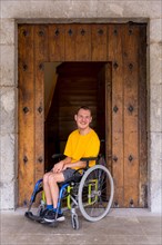 A disabled person in a wheelchair next to a wooden door