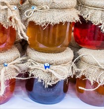 Various colored honey jars with fabric on lid in display