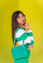 Portrait of a Caucasian girl in a white striped sweater on a green background