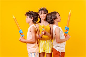 Brothers having fun with water pistols on summer vacations and aiming at camera
