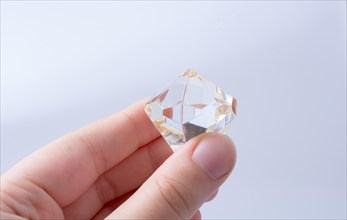 Hand holding a transparent diamond on a white background