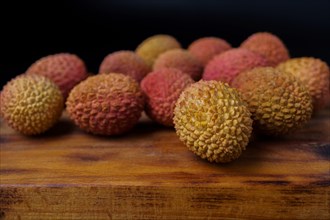 Group of fresh lychees on a wooden board with a black background