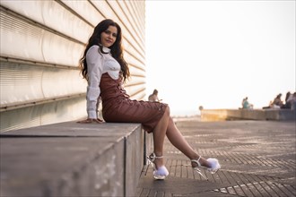 Portrait of a pretty brunette latin woman in a leather skirt sitting in the city on a sunset