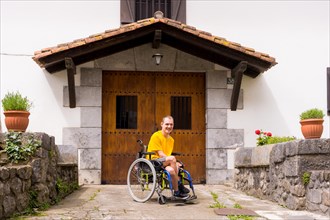 Portrait of a disabled person in a wheelchair in the entrance of his house smiling