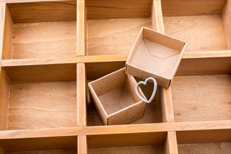 Open cardboard box inside a wooden box with compartments and a heart
