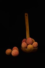 Fresh lychees in a wooden spoon isolated on a black background