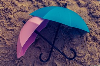 Pink umbrella on sand seen from the top