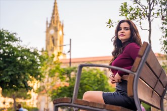 Portrait of a brunette woman in a leather skirt sitting in the city