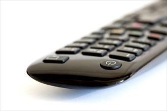 Close-up of a black remote control for a TV and TV