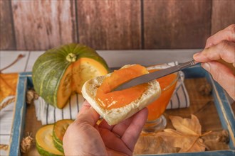 Woman spreading homemade pumpkin jam on a piece of toast with a knife