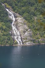 Kayakers paddling in front of a waterfall on a fjord in Norway