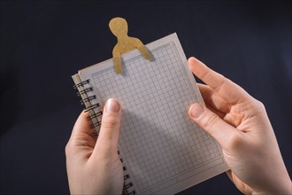 Man shape cut out of paper in notebbok in hand