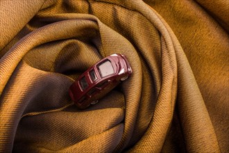 Miniature metal car on a brown fabric cloth
