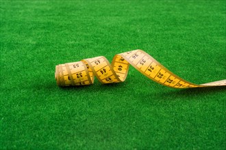 Yellow color measuring tape on green grass