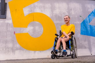 A disabled person in a public park with numbers on the wall in a wheelchair