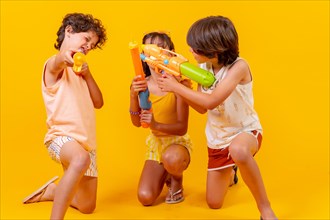 Kids having fun with water pistols on summer vacations and aiming at camera