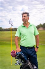 Portrait of a man playing golf together with the clubs on the green