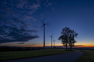 Three wind turbines with road at blue hour