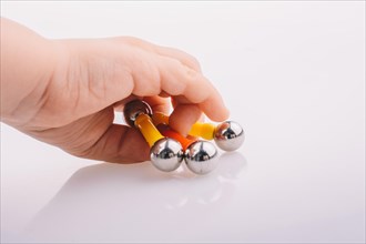 Hand holding magnet toy bars and magnetic balls on a white background