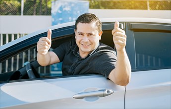 Happy driver giving a thumbs up on the road. safe driving concept. Satisfied driver man showing thumb up. Young driver man in the car showing thumb up
