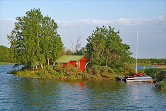 Small red cottage with boat on an island