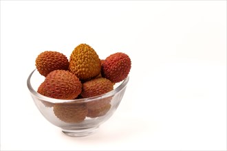 Fresh lychees in a clear glass bowl isolated on a white background