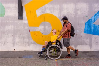 Disabled person in a wheelchair by a cement wall