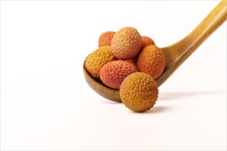 Fresh lychees in a wooden spoon isolated on a white background