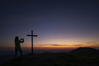 Mountaineer with mobile phone and sunrise in the background
