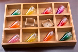 Colorful small bottles and small carton boxes in a wooden box in the view