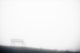 Mountain meadow with bench and fog in the background