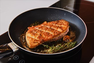 Crispy crosswise cut duck breast in frying pan with thyme and garlic