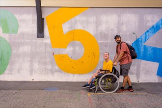 A disabled person in a wheelchair with a cement wall