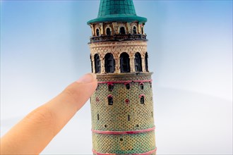 Hand pointing a model of the Galata Tower in Istanbul