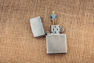 Man figurine in the chimney of a lighter on a textured as background