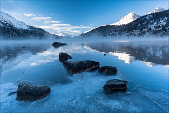 Lake St. Moritz with morning fog and ice in the foreground at sunrise
