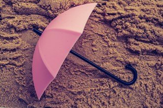 Pink umbrella on sand seen from the top