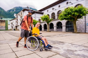 A disabled person in a wheelchair walking through the town square with a friend