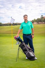 Portrait of a man playing golf along with the clubs on the green