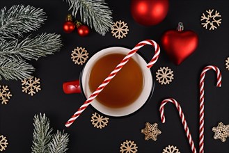 Cup of tea with Candy Cane and seasonal Christmas decoration on black background