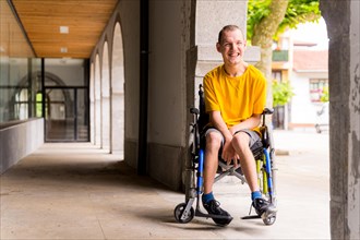 Portrait of a disabled person in a wheelchair smiling next to some columns in a doorway