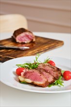Juicy grilled duck breast served on a plate with fresh arugula and corn salad