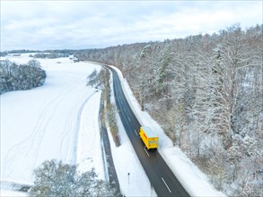 DHL car on winter road at the edge of the forest