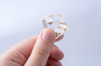 Hand holding a transparent diamond on a white background