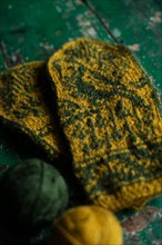 Hand-knitted gloves with pattern next to ball of wool