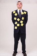 Smiling businessman on camera with blank sticky notes on his suit concepts of time management