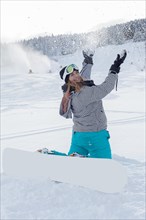 Woman with snowboard sitting in the snow