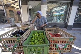 Egyptian man talking on the phone and selling vegetables in baskets