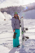 Woman with snowboard stands on ski slope