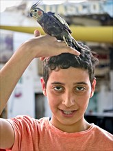 Young man looking directly into the camera with parakeet on his head Aqaba